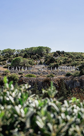 Signalétique "Château de Lastours" intégrée dans la garrigue, vue sur la colline végétalisée
